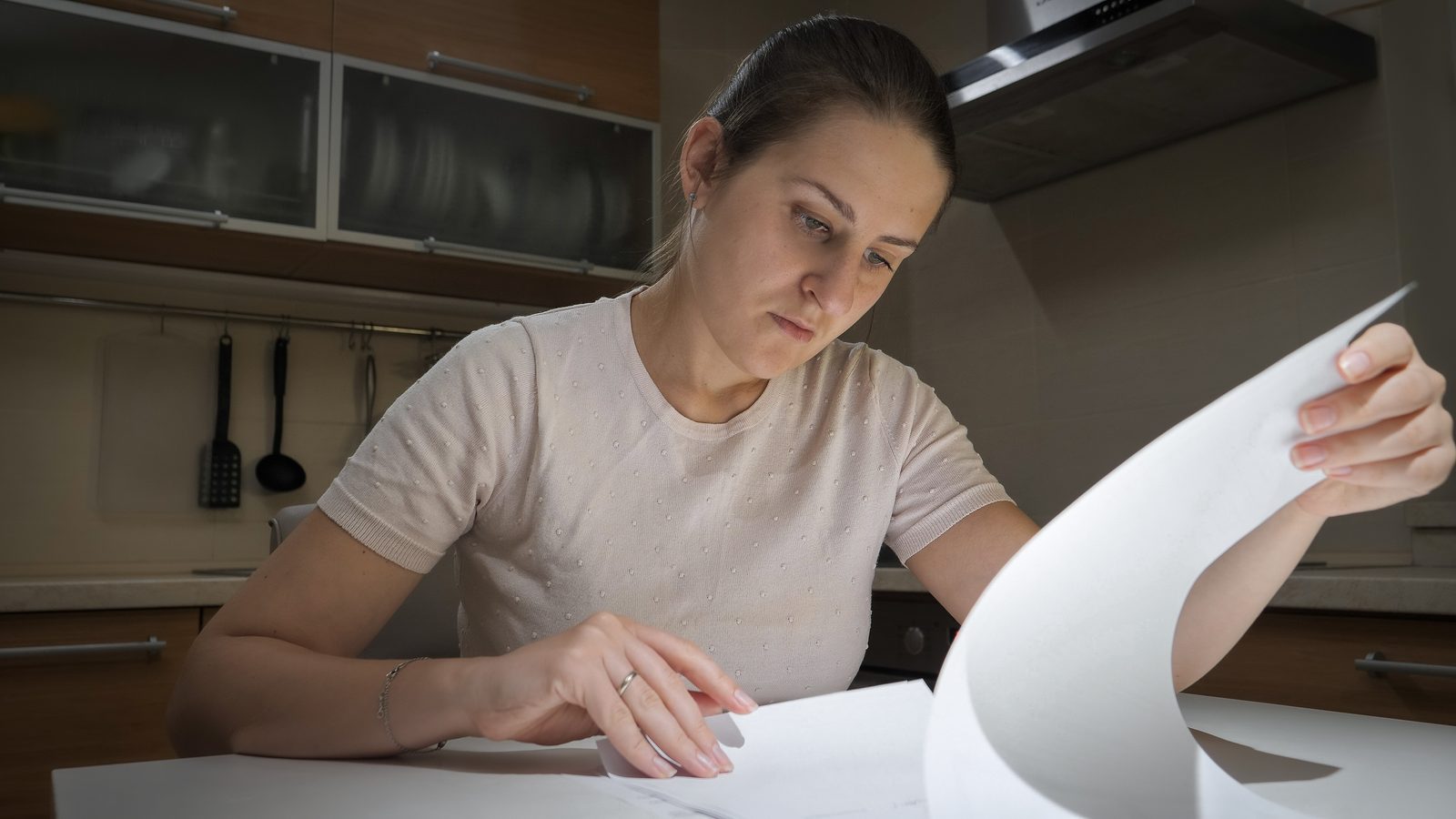 Woman reviewing a debt collection letter and credit report at her kitchen table