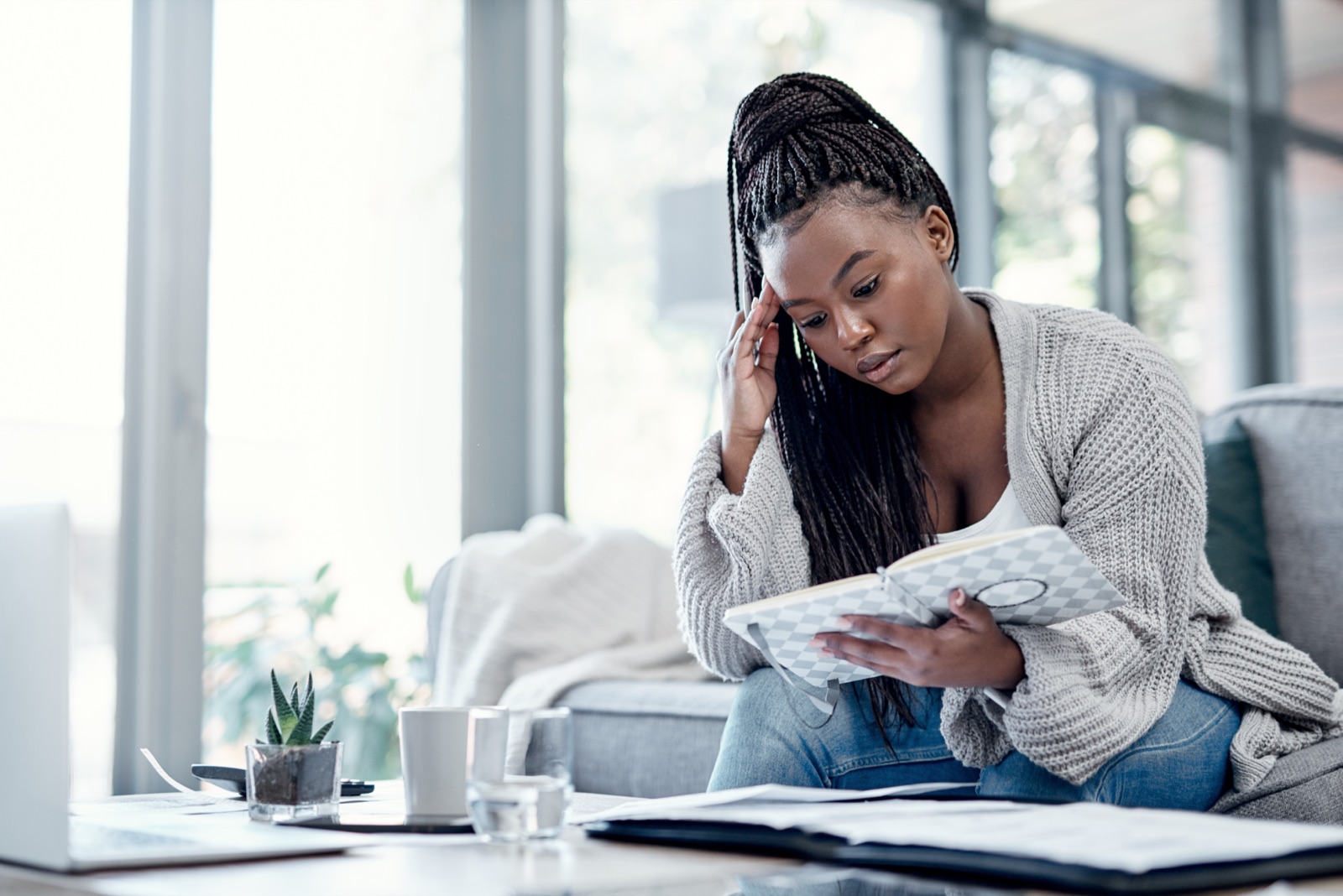 Woman reviewing paperwork and finances at home after noticing a late payment on her credit report