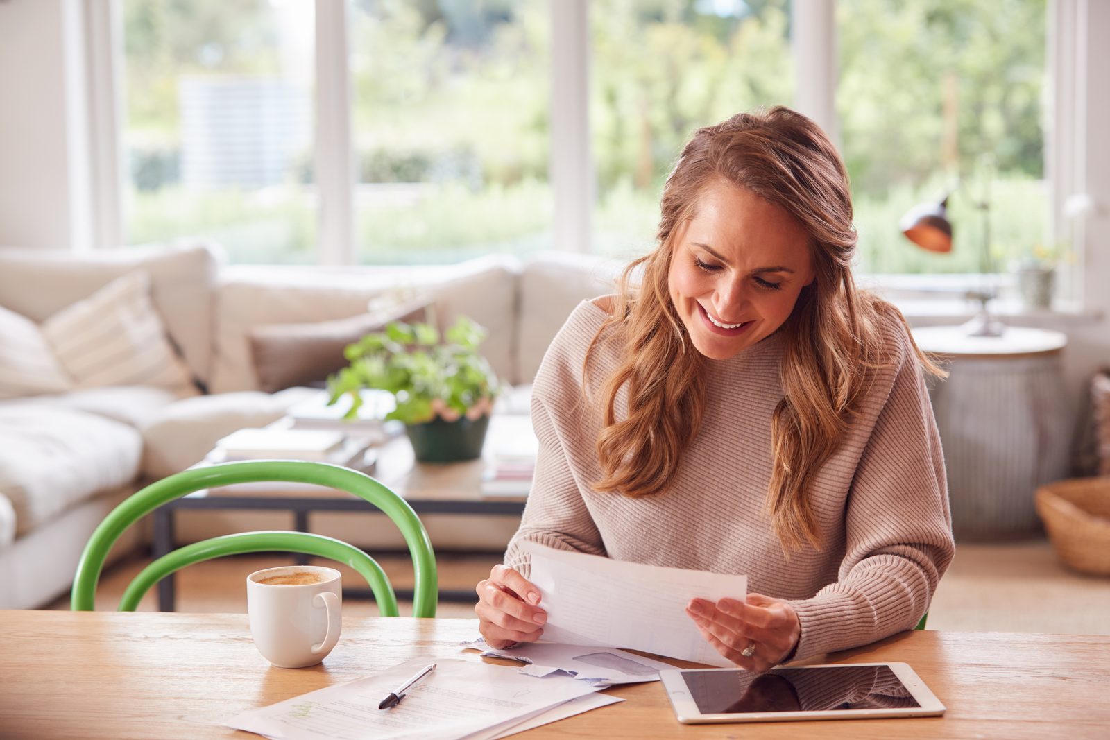 Woman reviewing a credit repair cost estimate and paperwork at her kitchen table